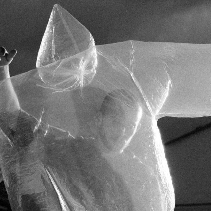 A person dancing with translucent body-shaped balloon in front of them.