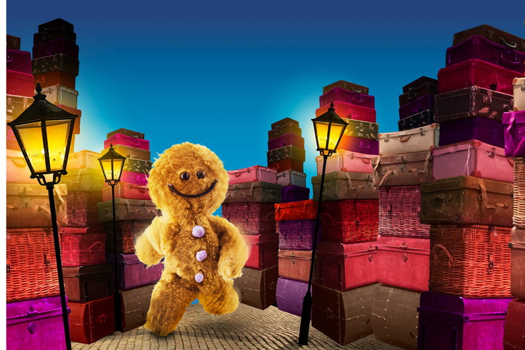 A fluffy gingerbread man in front of a pile of colourful boxes and street lamps