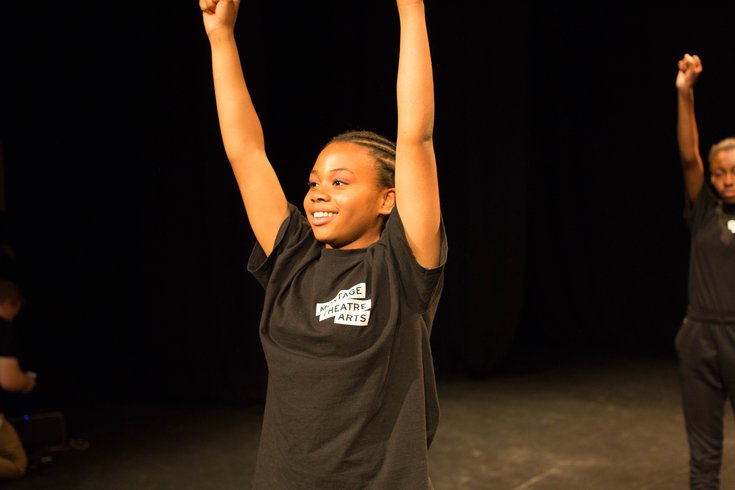 A student posing on stage in a black MTA t-shirt during a show.