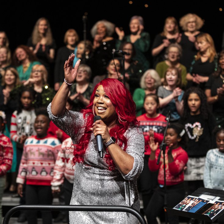 Lots of people of all different ages performing wearing festive jumpers