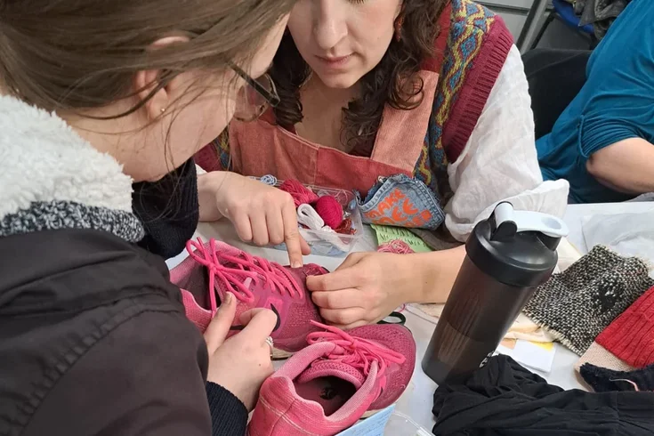 Women darning and fixing a pink pair of trainers