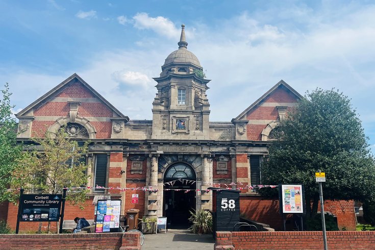 photo of Corbett Community Library, a Victorian redbrick and sandstone Carnegie building, in the sun with bunting stretched across the path