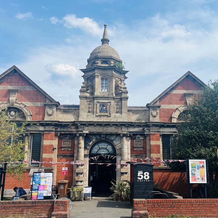 photo of Corbett Community Library, a Victorian redbrick and sandstone Carnegie building, in the sun with bunting stretched across the path