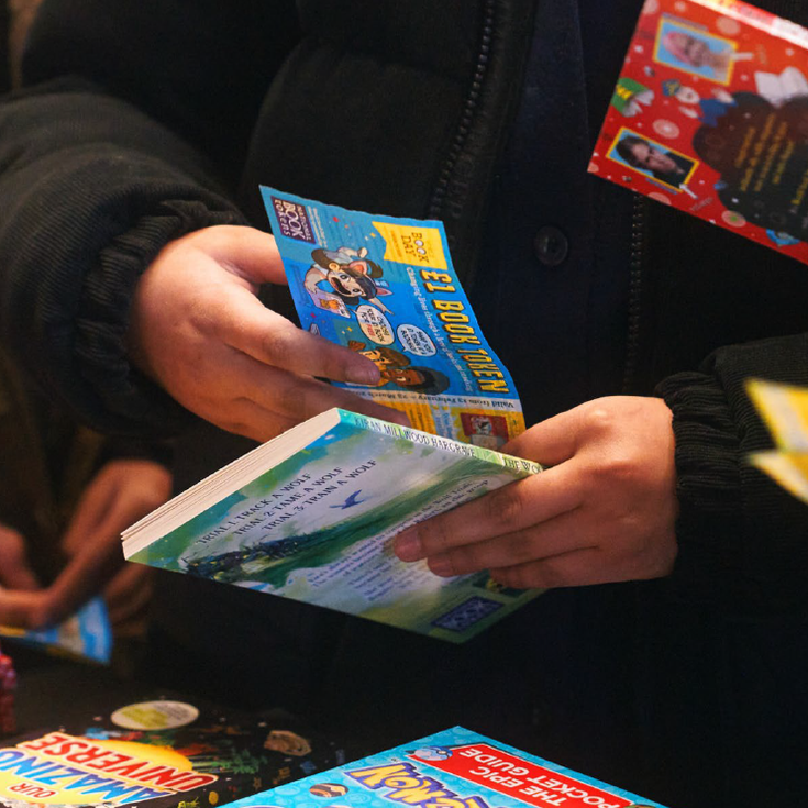 Close up of children's hands as they exchange World Book Day tokens for books
