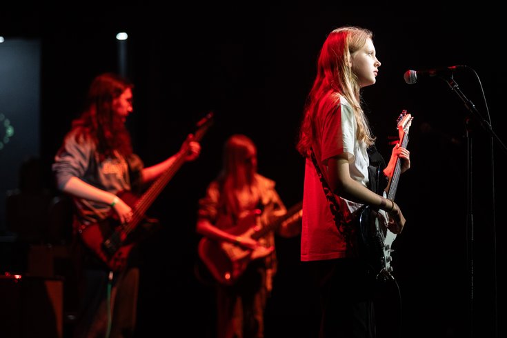 Young band members play guitar and bass on stage