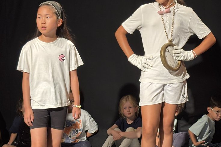 Two students pose in the middle of a scene, with one dressed in a white bunny costume and the other in a t-shirt and shorts.