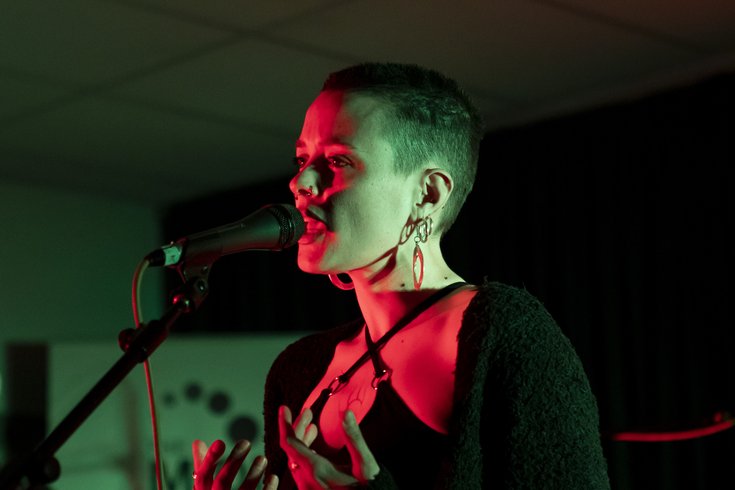 A female tutor and CAPs member, Barbara, with a buzz cut performs at The Midi Music Company’s 30th anniversary under red lighting.