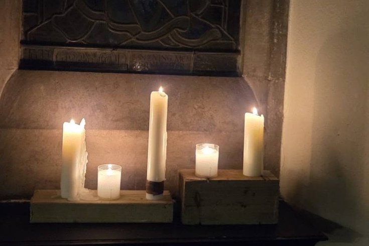 Wax candles burn on a stone church shelf