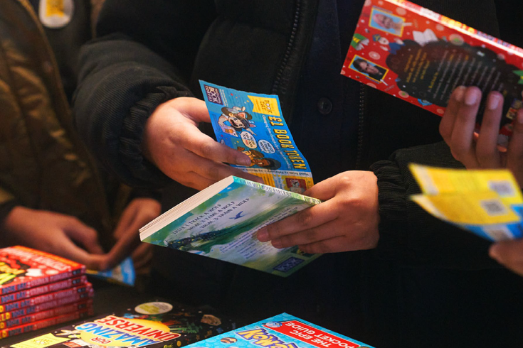 Close up of children's hands as they exchange World Book Day tokens for books