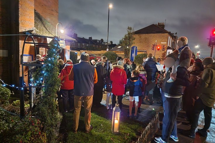 a group of people in colourful outfits gather to sing outside a church in twinkling lights
