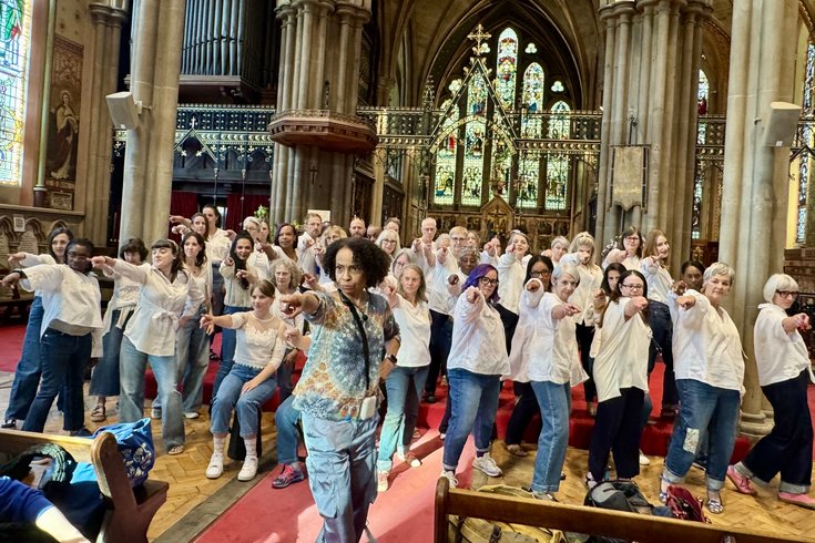 Group dressed in jeans and white tops all pointing in an ironic Spice Girls pose
