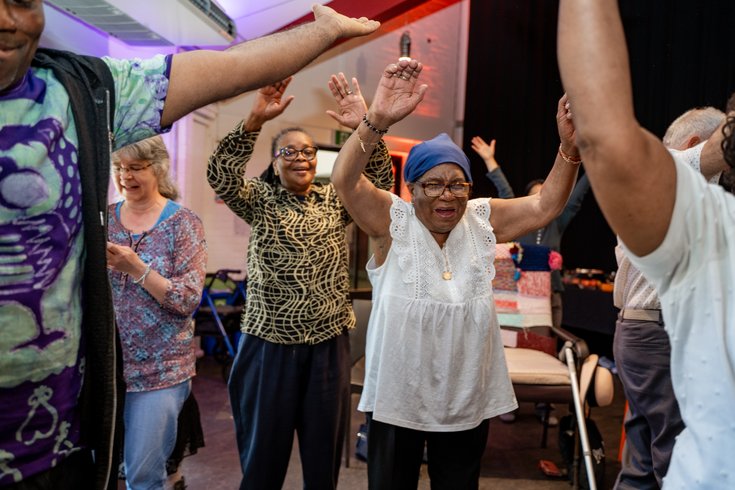 A group of elders dancing with their arms raised in the air. Credit Elena Ledgister.