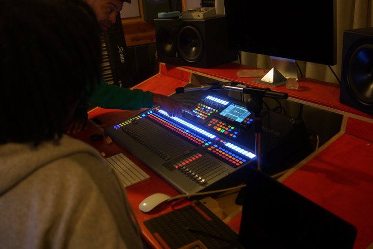 A person in a grey jumper, seen from behind, looks at a bright orange sound desk.