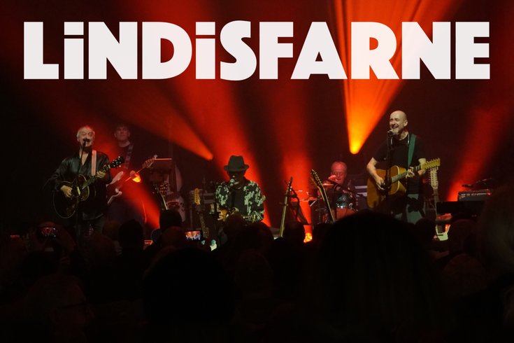 Word Lindisfarne with a group of musicians on the stage with a red light backdrop