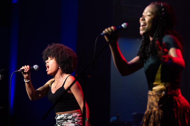Two young people sing into the mic