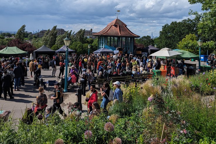 Event at the Horniman Bandstand with visitors and stalls, and London skyline in the background