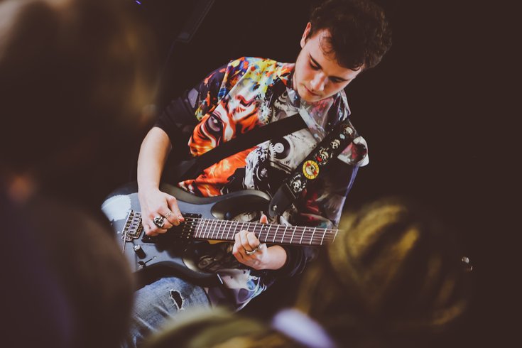 A young person plays the electric guitar.