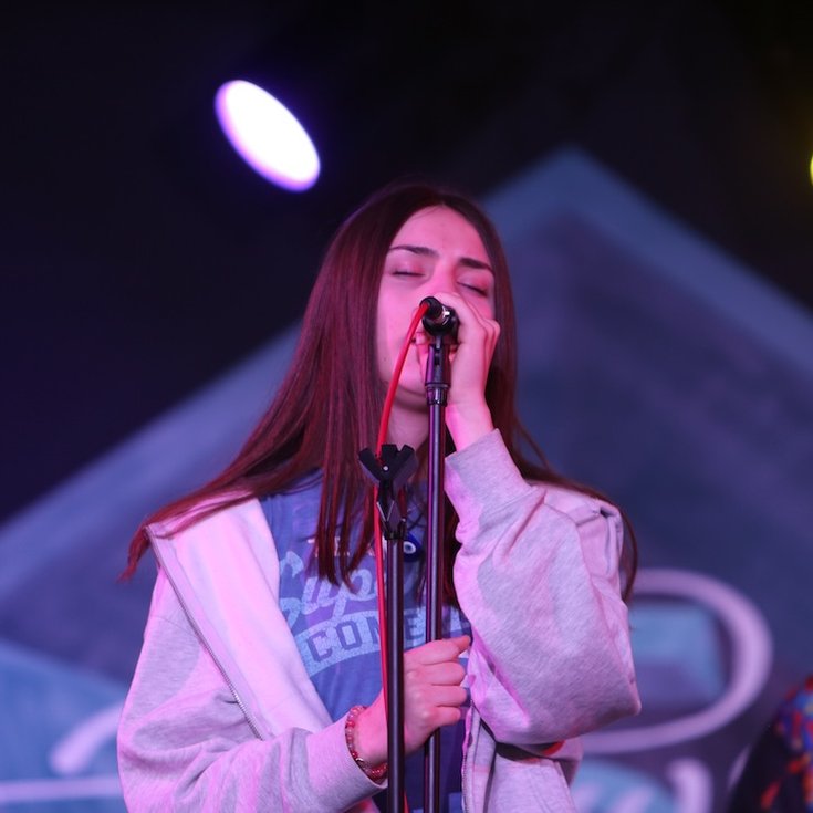 A young person sings into a mic.