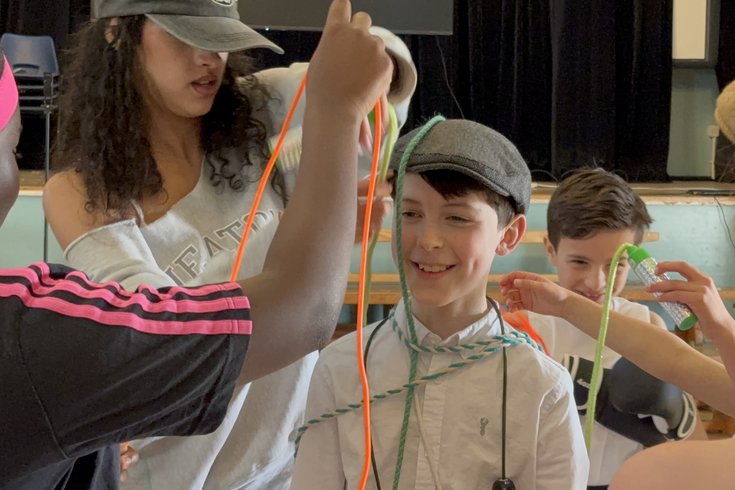 A student smiling at the camera as friends cover him in skipping ropes.