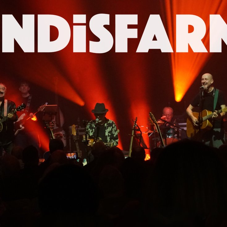 Word Lindisfarne with a group of musicians on the stage with a red light backdrop