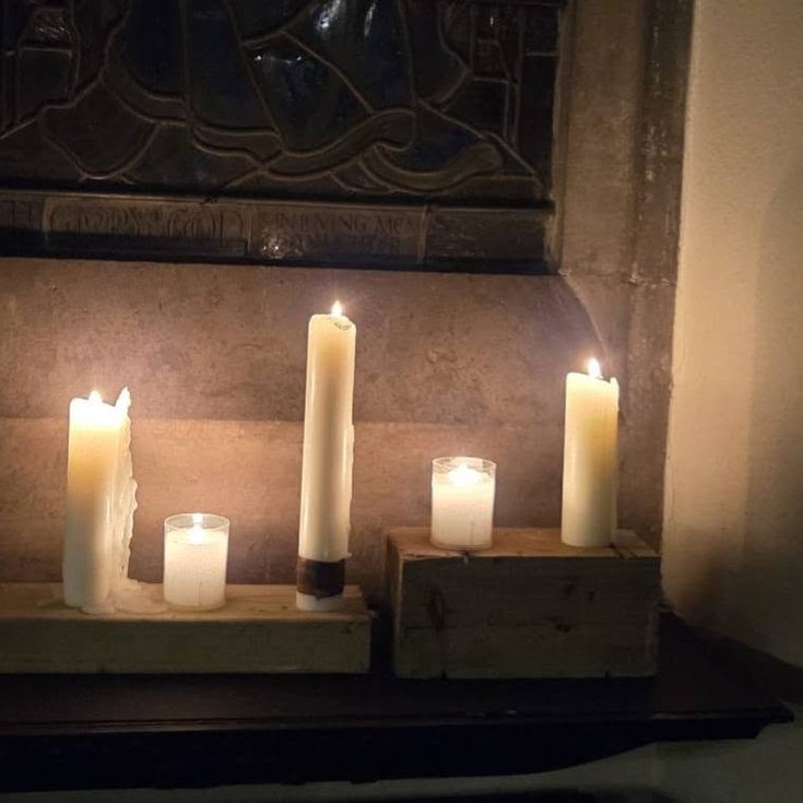 Wax candles burn on a stone church shelf