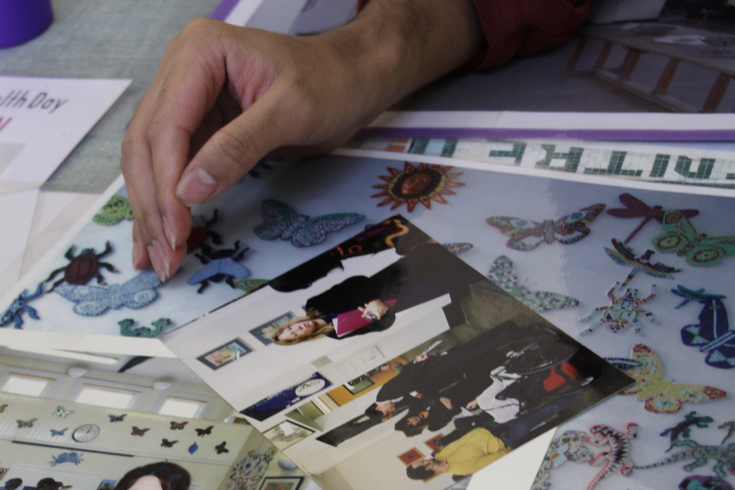 A photo of someone's hand on top of photographs showing different events, from Arts Network's archive.