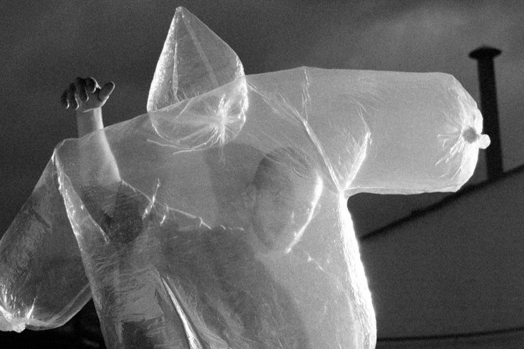 A person dancing with translucent body-shaped balloon in front of them.